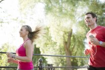 Mann und Frau joggen durch Park — Stockfoto