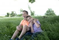 Мальчики сидят и играют в длинную траву — стоковое фото