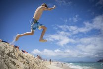Хлопчик стрибає в піщаних дюнах на пляжі — стокове фото