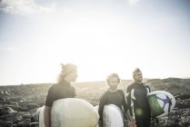Tres hombres preparándose para surfear - foto de stock