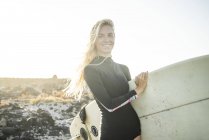 Женщина в гидрокостюме готовится к серфингу — стоковое фото