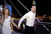 Couple run across Millennium Bridge — Stock Photo