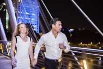 Couple courir à travers Millennium Bridge — Photo de stock