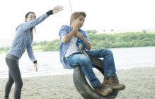 Woman and boy playing on tyre hanging from tree — Stock Photo