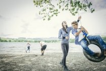 Family playing on tyre hanging from tree — Stock Photo