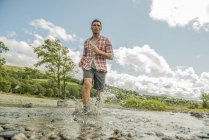 Людина перетинає мілководну річку — стокове фото