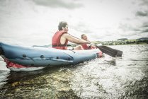 Homme et garçon en kayak pagayant loin du rivage — Photo de stock