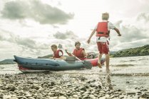 Uomo e due ragazzi in kayak remare via — Foto stock