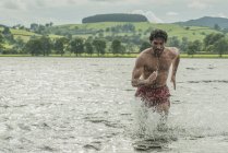 Uomo in forma che corre attraverso acque poco profonde — Foto stock