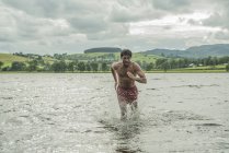 Hombre en forma corriendo a través de aguas poco profundas - foto de stock