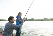 Father and son fishing from shore — Stock Photo