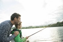 Padre e hijo pescando desde la orilla - foto de stock