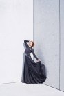 Donna in abito nero contro muro di marmo — Foto stock