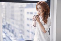 Frau im weißen Hemd trinkt Morgenkaffee — Stockfoto