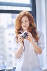 Woman in white shirt holds vintage camera — Stock Photo
