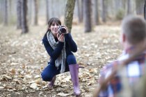 Жінка фотографує партнера в лісі — стокове фото