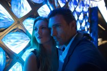 Casal banhado em luz azul na frente da luminária — Fotografia de Stock