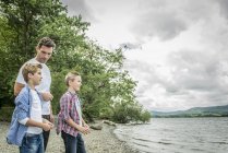 Man and two boys skimming stones — Stock Photo