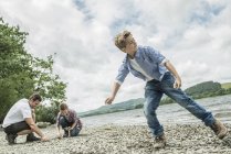 Man and two boys skimming stones — Stock Photo