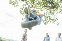 Famille jouer sur pneu accroché à l'arbre — Photo de stock