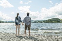 Мужчина и женщина стоят, держа руки на берегу — стоковое фото