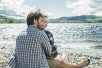 Man and woman sitting on shore — Stock Photo