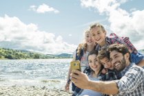 Family taking selfie on shore — Stock Photo