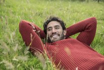 Uomo in maglione rosso rilassante in erba — Foto stock