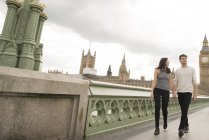 Pareja caminando de la mano a través del puente de Westminster - foto de stock