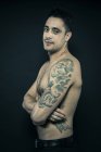 Tatuato uomo posa con le braccia incrociate — Foto stock