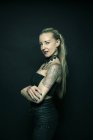 Donna in piedi con le braccia tatuate incrociate — Foto stock