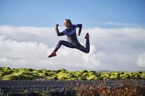 Frau springt durch menschenleere Schotterstraße — Stockfoto