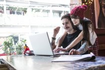 Pareja trabajando en el ordenador portátil en la cafetería - foto de stock
