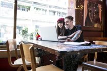 Пара, работающая за ноутбуком в кафе — стоковое фото