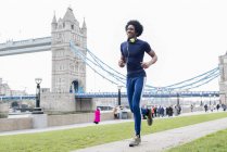 Man jogging past Tower Bridge — Stock Photo