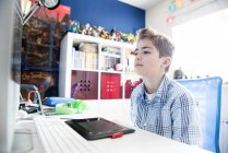 Хлопчик сидить за комп'ютером — стокове фото