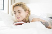 Woman lying on bed with book — Stock Photo