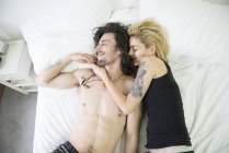 Татуированная пара обнимается на кровати — стоковое фото