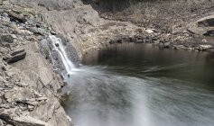 Водопад, текущий в старый заброшенный карьер — стоковое фото