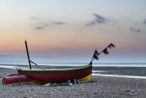 Маленькі рибальські човни на пляжі на сході сонця — стокове фото