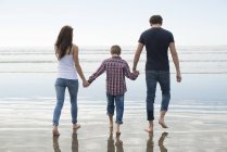 Couple and son walking in sunshine on beach — Stock Photo