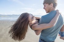 Mann trägt Partnerin über Strand — Stockfoto