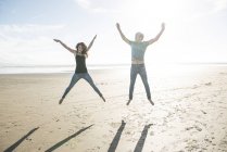 Couple jumping in sunshine on beach — Stock Photo