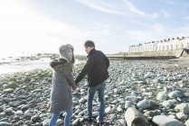 Пара ходить, тримаючи руки на пляжі — стокове фото