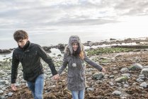 Coppia che cammina tenendosi per mano sulla spiaggia — Foto stock
