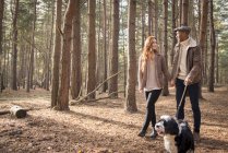 Pareja fuera con perro en bosque paseo - foto de stock