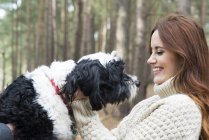 Woman stroking dog on forest walk — Stock Photo