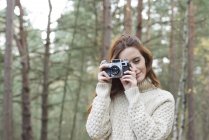 Woman using vintage camera in forest — Stock Photo