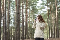 Mulher usando câmera vintage na floresta — Fotografia de Stock