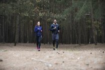 Young couple running through forest — Stock Photo